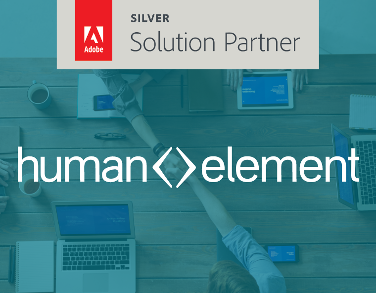 A tabletop with laptops, tablets, and coffee cups; people reaching in for a group fist bump. Overlaid text reads human element and Adobe Silver Solution Partner.