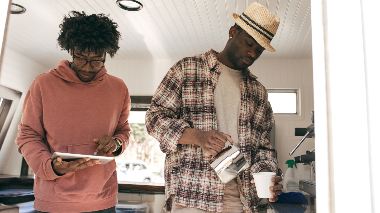 two men working in coffee shop, ordering supplies online and pouring coffee