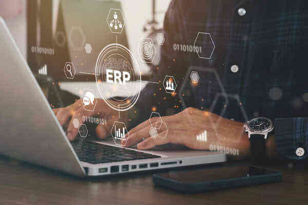 A person typing on a laptop with digital graphics overlaid, including the text ERP and various technology icons, symbolizing enterprise resource planning software.