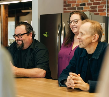 three adults near a kitchen table in a work break room